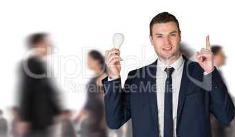 Composite image of businessman holding light bulb and pointing