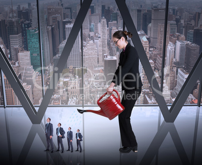 Composite image of businesswoman watering tiny businessman