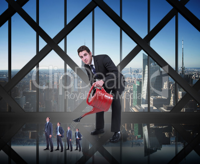 Composite image of businessman watering tiny businessman