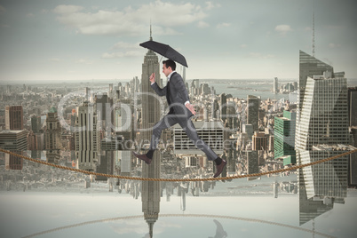 Composite image of businessman jumping on tightrope holding an u