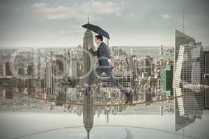 Composite image of businessman jumping on tightrope holding an u