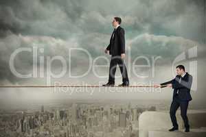 Young business man pulling a tightrope for businessman