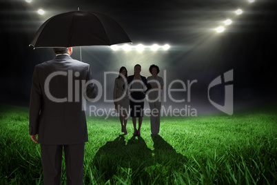 Composite image of mature businessman holding an umbrella