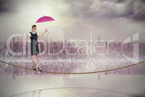 Composite image of pretty redhead businesswoman holding umbrella