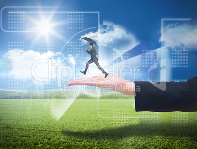 Composite image of businessman jumping holding an umbrella