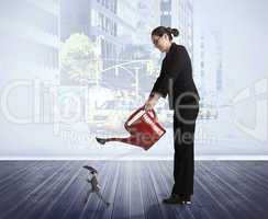 Composite image of businesswoman watering tiny businessman
