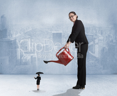 Composite image of businesswoman watering tiny businesswoman