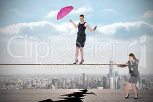 Young business woman pulling a tightrope for businesswoman