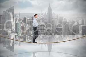 Composite image of serious asian businessman on tightrope