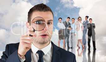 Composite image of businessman looking through magnifying glass