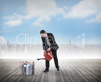 Composite image of businessman watering tiny business team