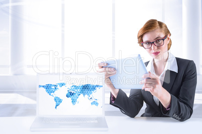 Composite image of redhead businesswoman using her tablet pc Composite image of redhead businesswoman using her tablet pc