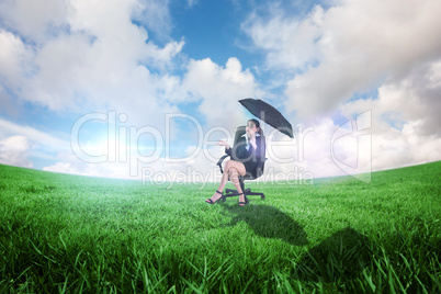 Composite image of young businesswoman holding umbrella