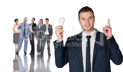 Composite image of businessman holding light bulb and pointing