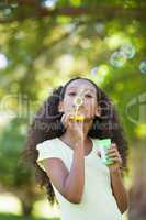 Young girl blowing bubbles in the park