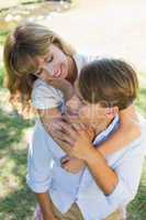 Man giving his pretty girlfriend a piggy back in the park smilin