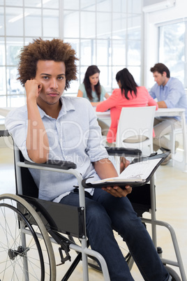 Stern businessman in wheelchair holds planner and frowns at came