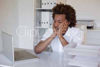 Casual businessman feeling exhausted at his desk