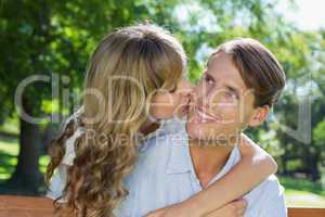 Affectionate couple relaxing on park bench together