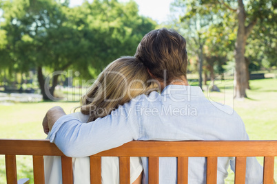 Affectionate couple relaxing on park bench together