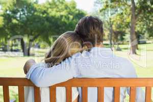 Affectionate couple relaxing on park bench together