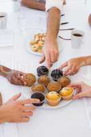 Business people taking muffins from plate
