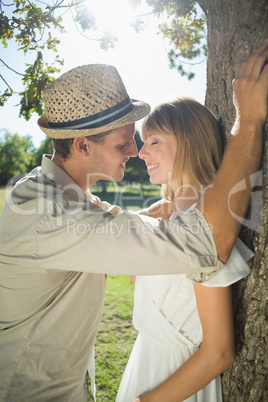 Cute couple leaning against tree in the park