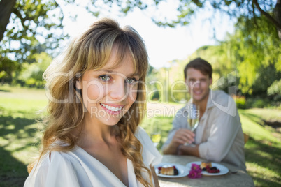 Cute blonde smiling at camera with boyfriend in background