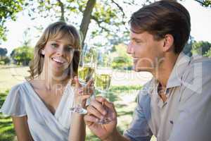 Cute smiling couple sitting outside toasting with champagne