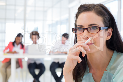 Attractive casual businesswoman holding pencil focusing