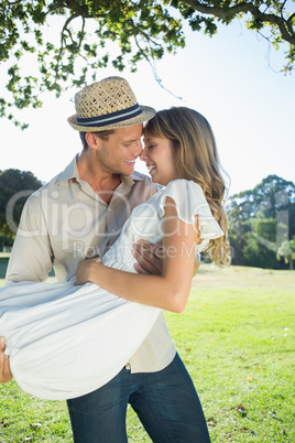 Cute blonde smiling while being lifted by boyfriend in the park