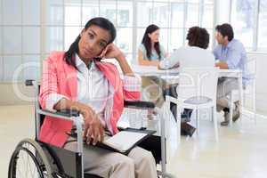 Woman with disability frowning with coworkers are in background