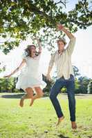 Cute couple jumping in the park together