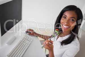 Casual pretty businesswoman eating a salad at her desk