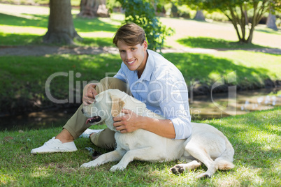 Handsome smiling man with his labrador in the park