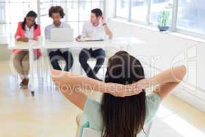 Businesswoman relaxes with hands behind her head