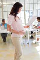 Pregnant woman touches bump and reads document