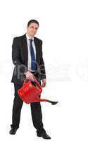Businessman watering with red can and smiling at camera