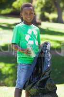 Young boy in recycling tshirt picking up trash