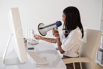 Angry businesswoman shouting in megaphone at phone