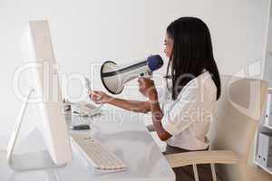 Angry businesswoman shouting in megaphone at phone