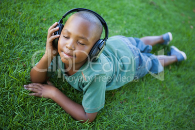 Little boy lying on grass listening to music with eyes closed Little boy lying on grass listening to music with eyes closed