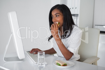 Pretty businesswoman eating a sandwich at her desk