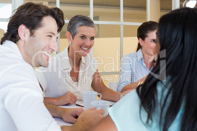 Business people smile and chat while enjoying hot drinks