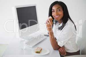 Pretty businesswoman having a sandwich at her desk