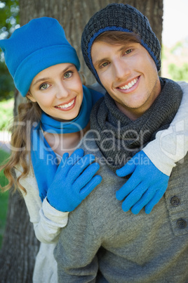 Cute couple embracing in the park smiling at camera