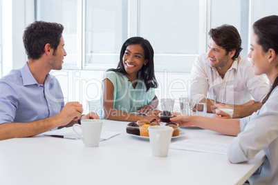 Work colleagues chatting in board room while enjoying coffee and