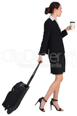 Businesswoman pulling her suitcase holding coffee