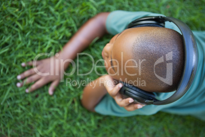 Little boy lying on grass listening to music