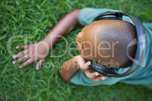 Little boy lying on grass listening to music